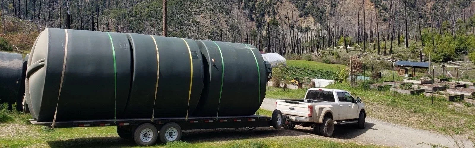 Forestscapes truck hauling 3 big water tanks to a client's property